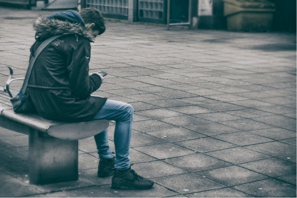 Image of young man sitting alone with his phone